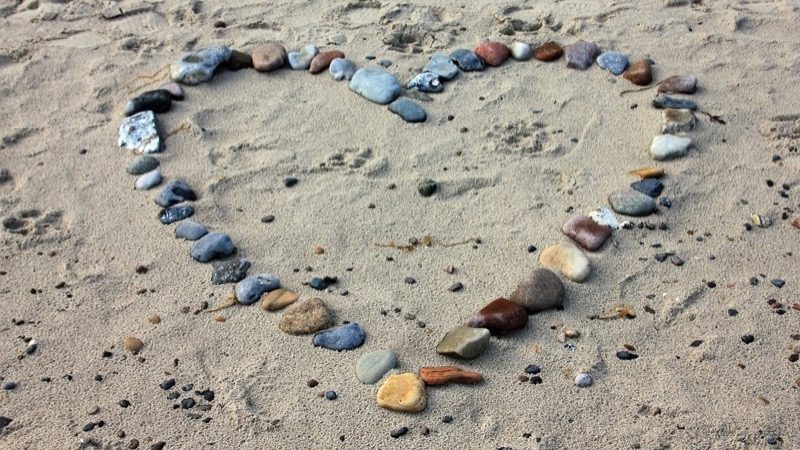 Kærlighed symboliseret af et hjerte af sten på en strand