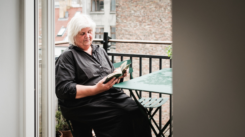Dorte Veien sidder på sin altan med grønne stole og bord og læser en bog.