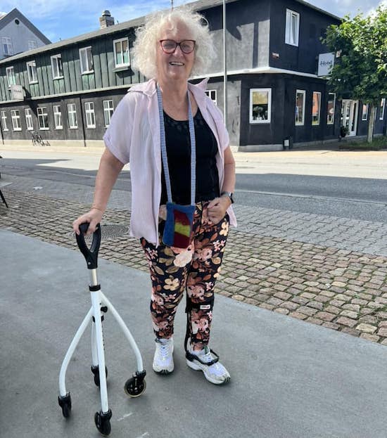 71-årige Anne Jacobsen står på fortov og støtter sig til en firhjulet stok