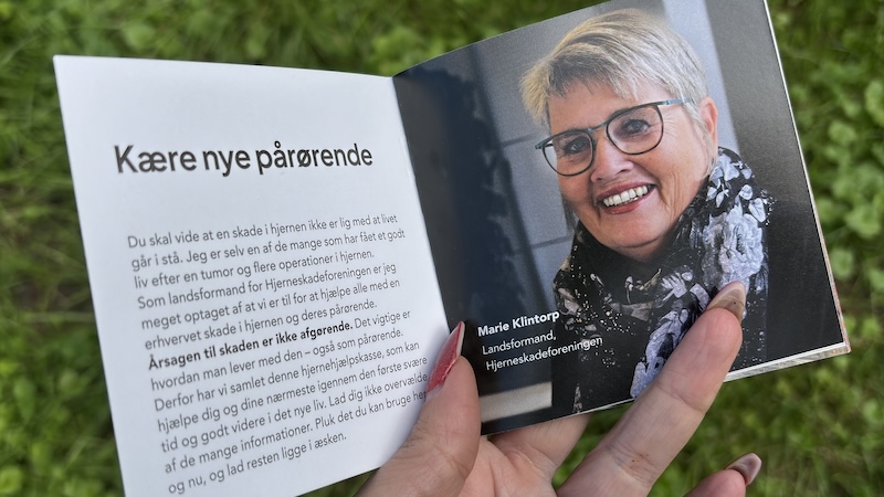 Opslag i Hjerneskadeforeningens lille pixibog til nye pårørende, som er en del af Hjernehjælpskassen. På venstresiden står en hilsen fra landsformand Marie Klintorp, på højresiden et portræt af hende.