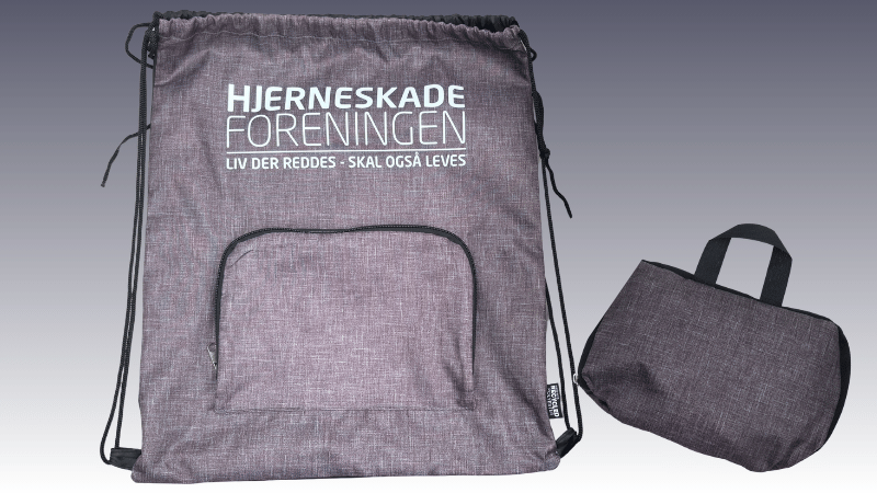 Grå gymnastikpose med Hjerneskadeforeningens logo og teksten “Liv der reddes – skal også leves”.